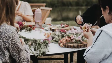 People create flower arrangements at an outdoor table.