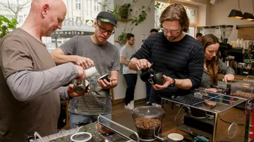 Kaffeetrinker bereiten Getränke in einem hellen Café zu.