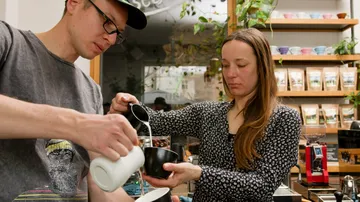 Zwei Personen bereiten Kaffee in einem Café zu.