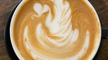 Kaffeetasse mit schaumiger, herzförmiger Latte-Art.