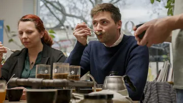 Personen essen in einem hellen Raum; Kaffee wird genossen.