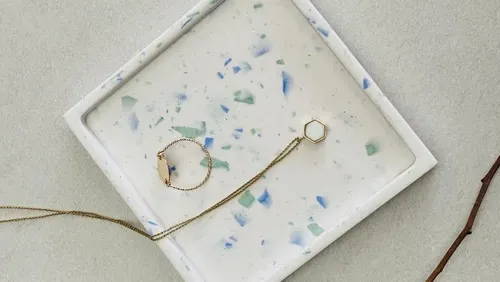 Goldschmuck liegt auf einer minimalistischen, dekorativen Schale.