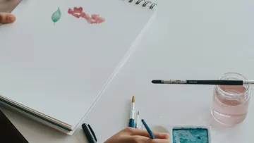 Skizze von Blättern und Blumen, Farben auf Tisch eingesetzt.