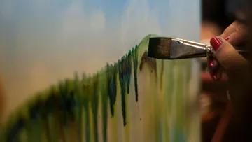 Pinsel malt grüne Striche auf eine Leinwand im Kunststudio.