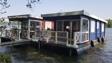 Schwimmende Häuser an einem ruhigen Gewässer mit Pflanzen.