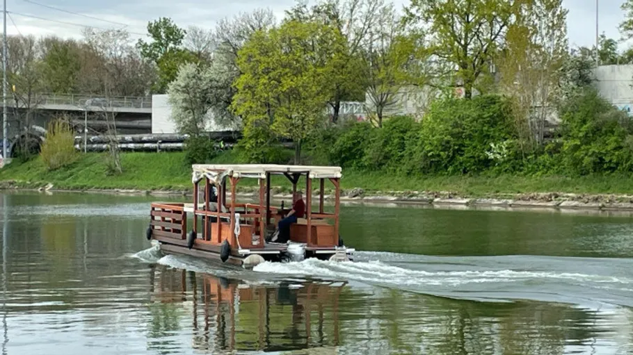 Ein Boot fährt auf einem ruhigen Fluss zwischen Bäumen.
