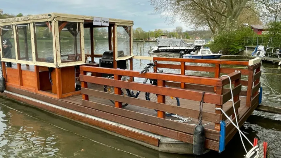 Ein Holzboot mit Überdachung liegt am Ufer.