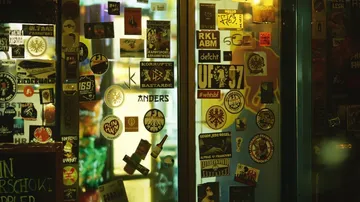 Window full of stickers, reflecting the city's nightlife.