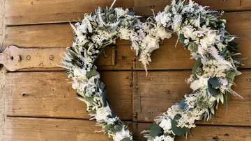 Heart-shaped wreath of white flowers on wooden wall