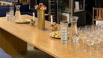 Wooden table with drinks, candles and snacks in a modern space.