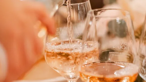 Gläser werden mit sprudelndem Getränk gefüllt, festliche Atmosphäre.