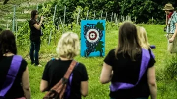 Gruppe schaut auf ein Ziel mit Traubenmotiv im Weinberg.