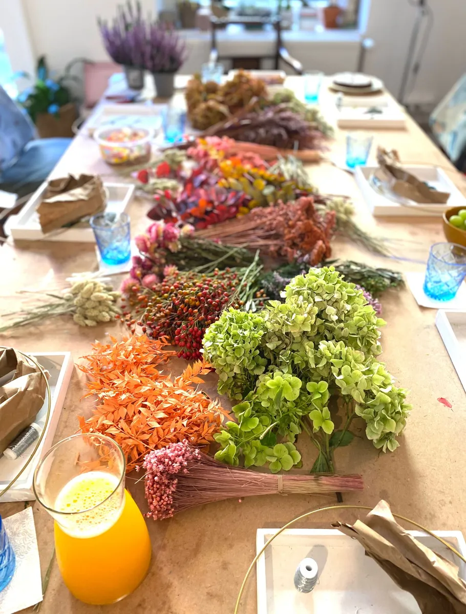 Bunte Trockenblumen auf einem Tisch, umgeben von Leckereien.