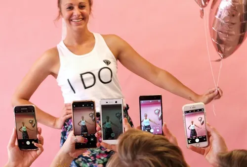 Woman posing with balloon surrounded by multiple cellphones.