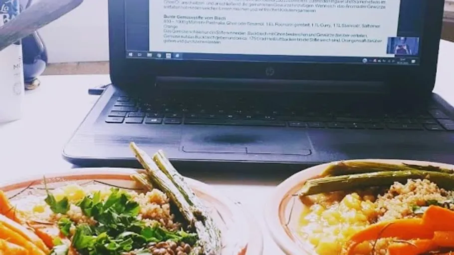 Two plates of healthy food next to a laptop.