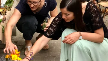 Two women are picking flowers at a market stall.