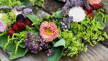 Bunte Blumen und Beeren liegen auf einem Holztisch.
