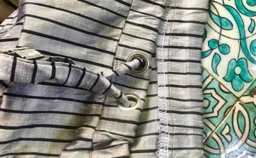 Striped piece of fabric with eyelets on decorative tile floor