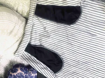 Striped shorts lie on a bed with other clothes.
