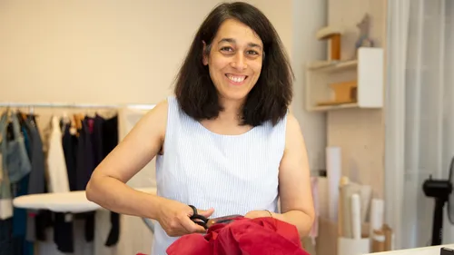 Woman cuts red fabric in a creative studio.