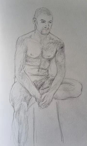 Man sits naked, holds hands together, sketches artfully.