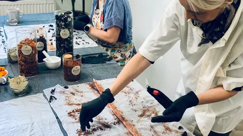 Woman places natural materials on silk cloth in the room during workshop.