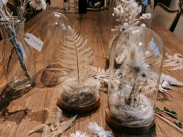 Glass bells with dried flowers on a wooden table.