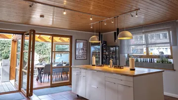 Moderne Küche mit Holzdetails, beleuchtet und offen für Garten.