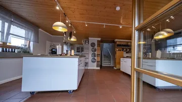 Helle Küche mit Insel, Stühlen und Treppe im Hintergrund.