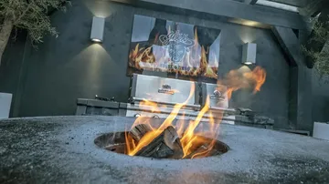 Fire is burning in a barbecue area with grills.