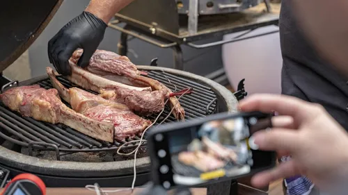 Meat is grilled while someone is taking a photo.