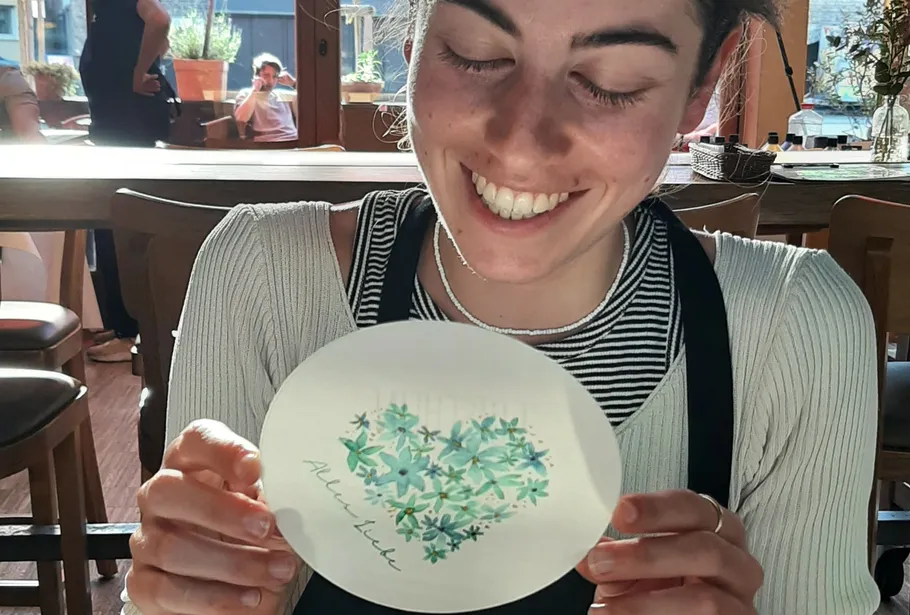 A woman is holding a hand-drawn card with a heart.