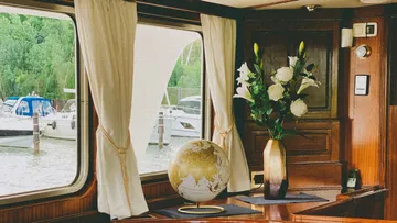 The globe and flowers are on a table in the boat.