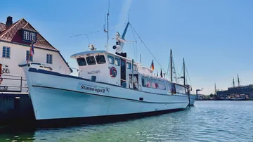 A boat is moored on the dock in the harbor in sunny weather.