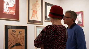 Zwei Personen betrachten nackte Kunstwerke in einer Galerie.