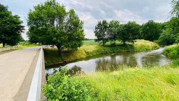 The river flows quietly between trees and meadows.
