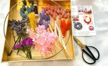 Colourful dried flowers lie next to frames and scissors.