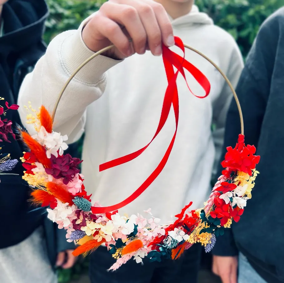 A floral wreath is held by hands and decorated.