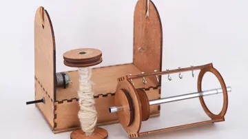 Holzmaschinen mit Spulen, schnurrenden Fäden und Spindelhaltern.