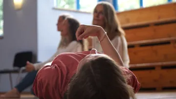 One person lies relaxed on the floor, others sit quietly.