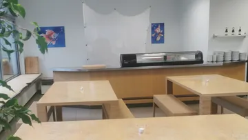 A wooden counter is empty in a bright restaurant.