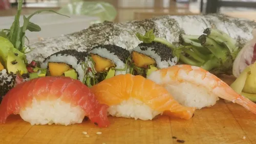 Sushi wird auf einem Holzbrett serviert, umgeben von frischen Zutaten.