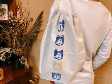 A person is wearing a bag with bear motifs.