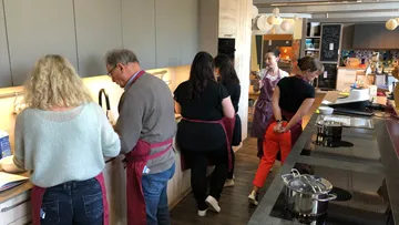 Gruppe kocht in modernem Küchenumfeld mit Praxisanleitung.