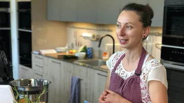 Eine Frau steht in einer modernen Küche und spricht.