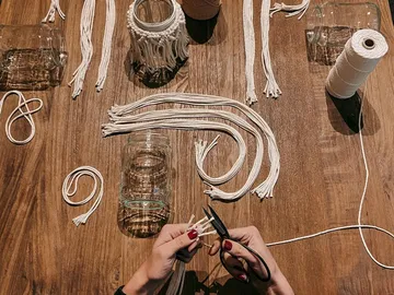 Glass jars are lying on a table while someone is cutting.