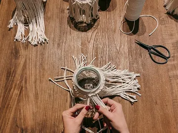 Glas wird mit geflochtenem Material auf Holzoberfläche gestaltet.