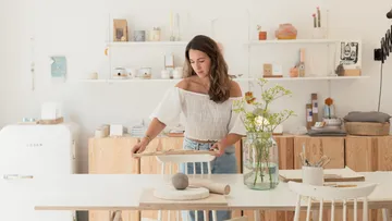 Woman sets up a table in a bright, minimalistic room.