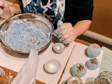 A person forms blue bath bombs at the table.