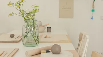 Vase mit Blumen steht auf einem Tisch mit Materialien.